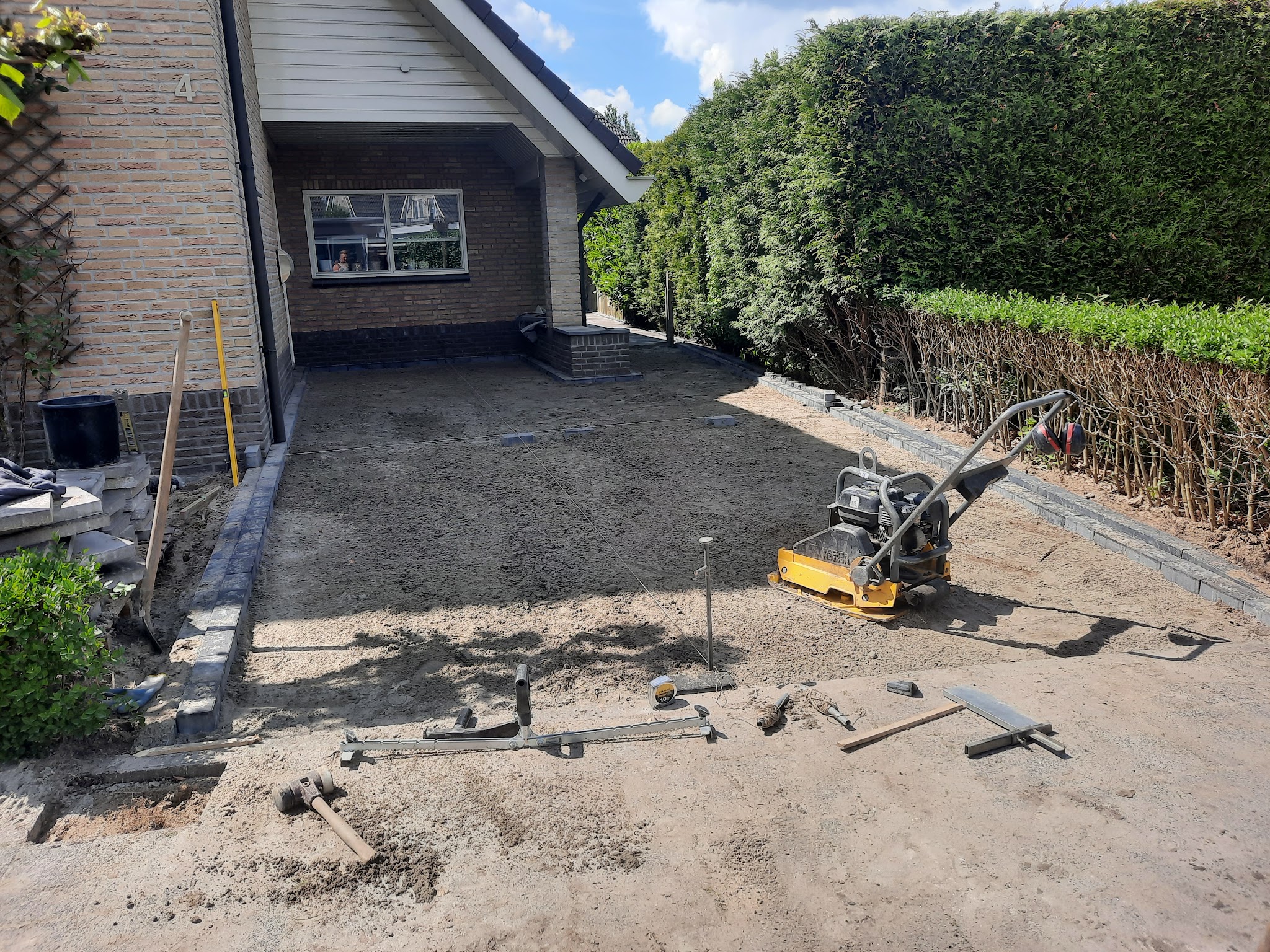 Oprit in voorbereiding: egaal zandbed, trilplaat en afgezette randen voor een garage