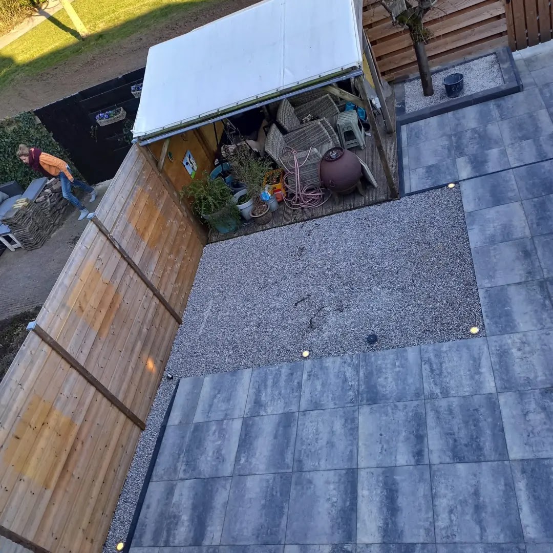 Bovenaanzicht van een terras met grijze tegels, grindbed en grondspots